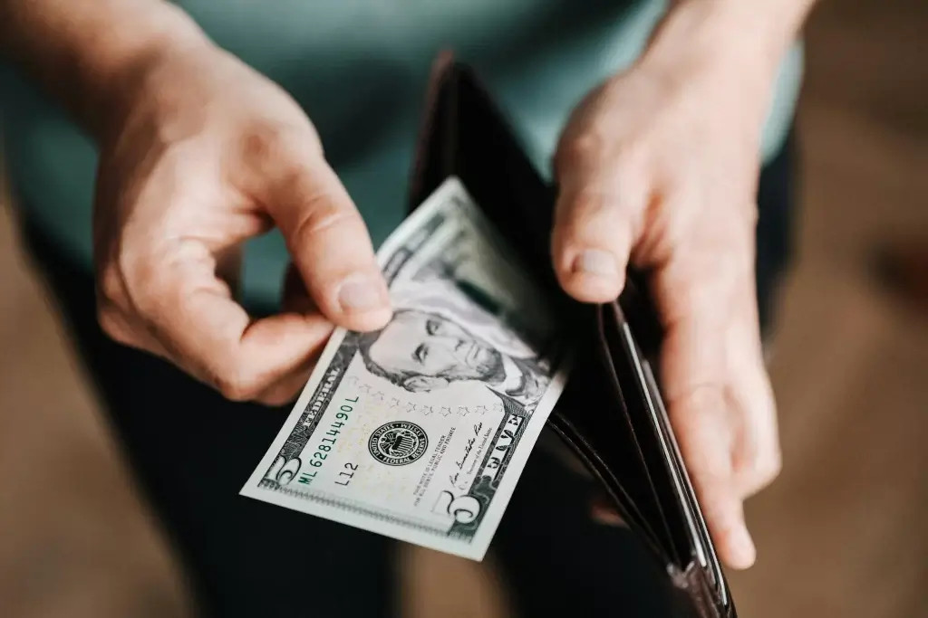 A man emptying his wallet due to excessive interchange fees.