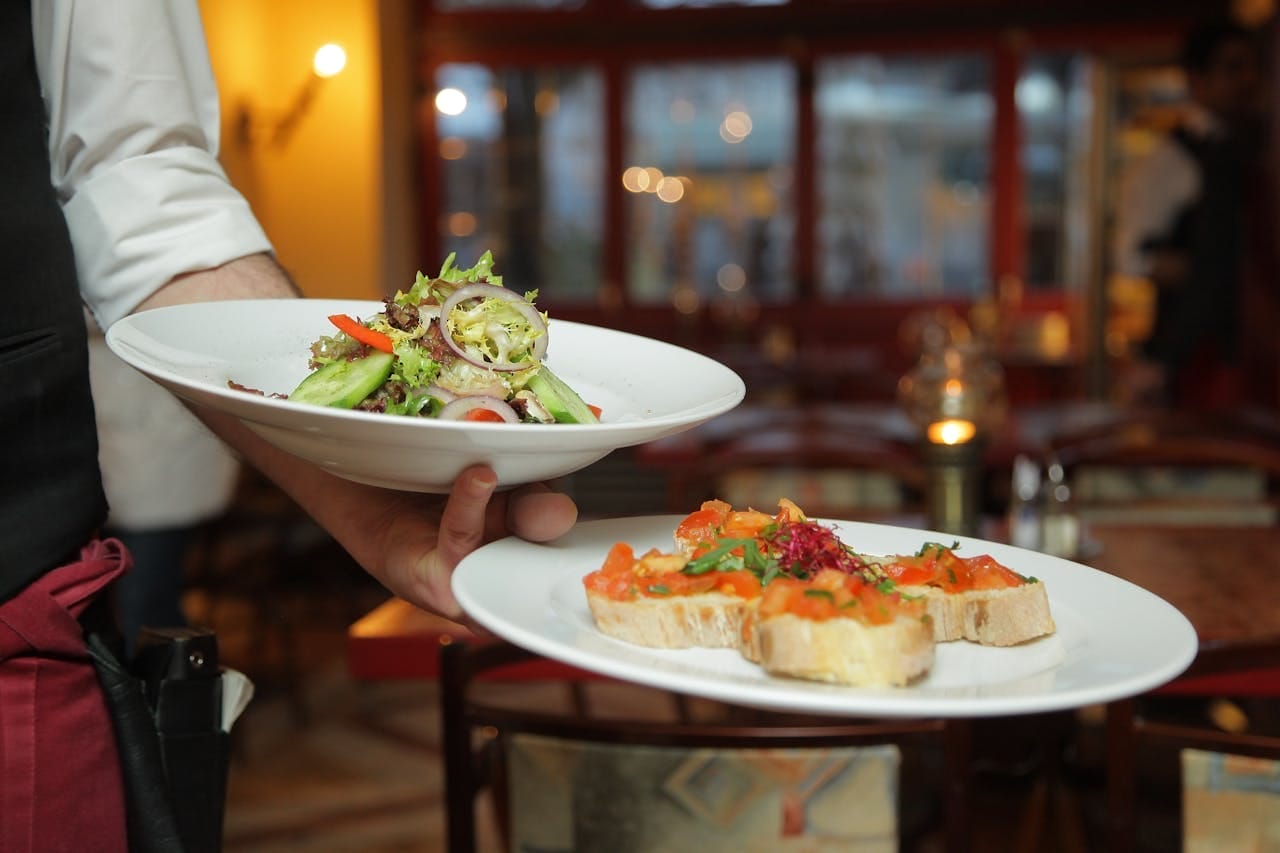Pastries are carried by a waiter on two plates.