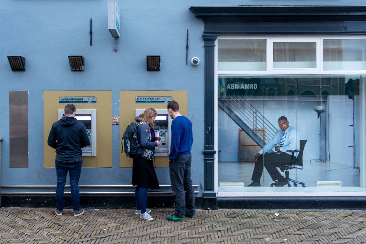 Several people standing next to ATMs.
